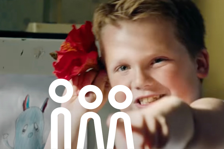 Szene aus dem Film mit dem Jungen, der sich eine rote Blume ans Haar hält.