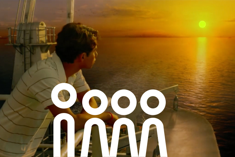 Der junge Pi Patel schaut von der Reling eines großen Schiffes aus auf den Sonnenuntergang am Horizont.