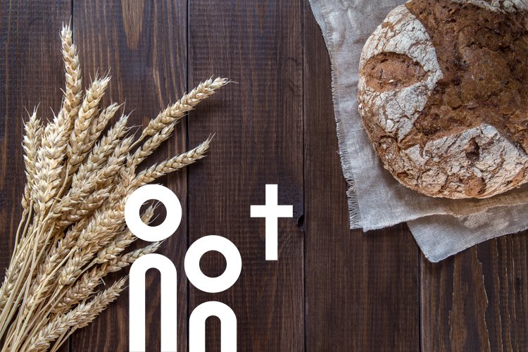 Weizenkorn und Brot auf einer dunkelbraunen Holztafel.