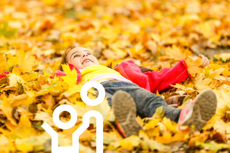 Liegendes Kind im Herbstlaub.