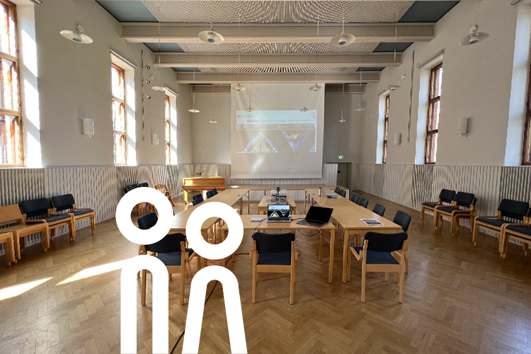 Blick in den Gemeindesaal in Helsinki mit Tischen und Leinwand.