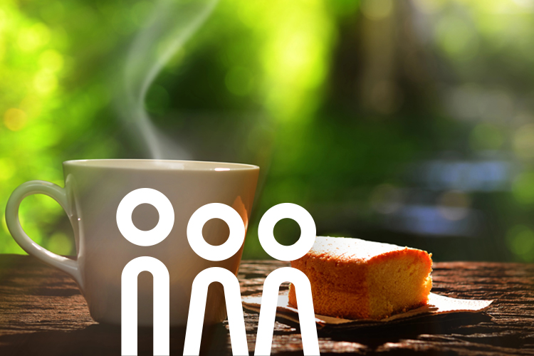 Sommercafé im Garten des Seniorenwohnheims Keramikbecher mit Heißgetränk und einem Stück Kuchen daneben.