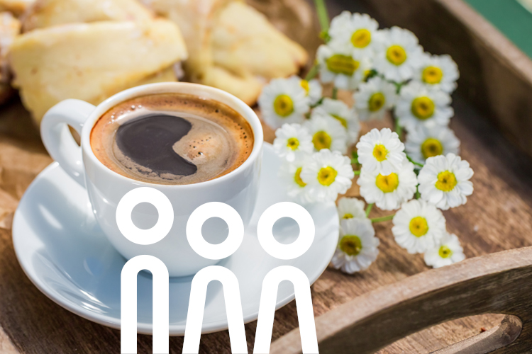 Tasse Kaffee auf einem Tablett mit weißen Sommerblumen und Gebäck.