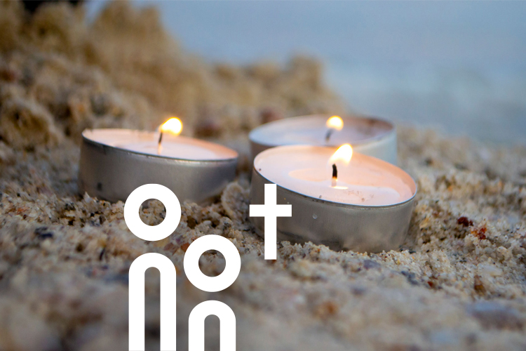 Drei Teelichter auf dem Sandstrand.