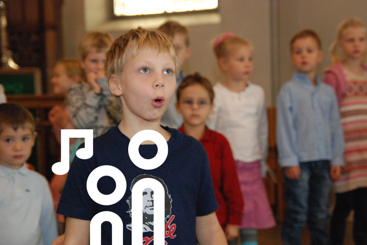 Singendes Kind vor anderen mitsingenden Kindern im Altarraum.