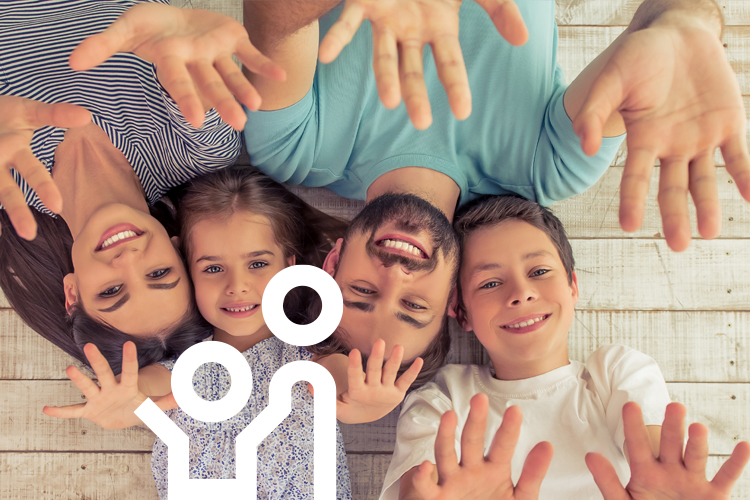 Eine auf dem Boden liegende Familie streckt ihre Arme und Hände hoch.